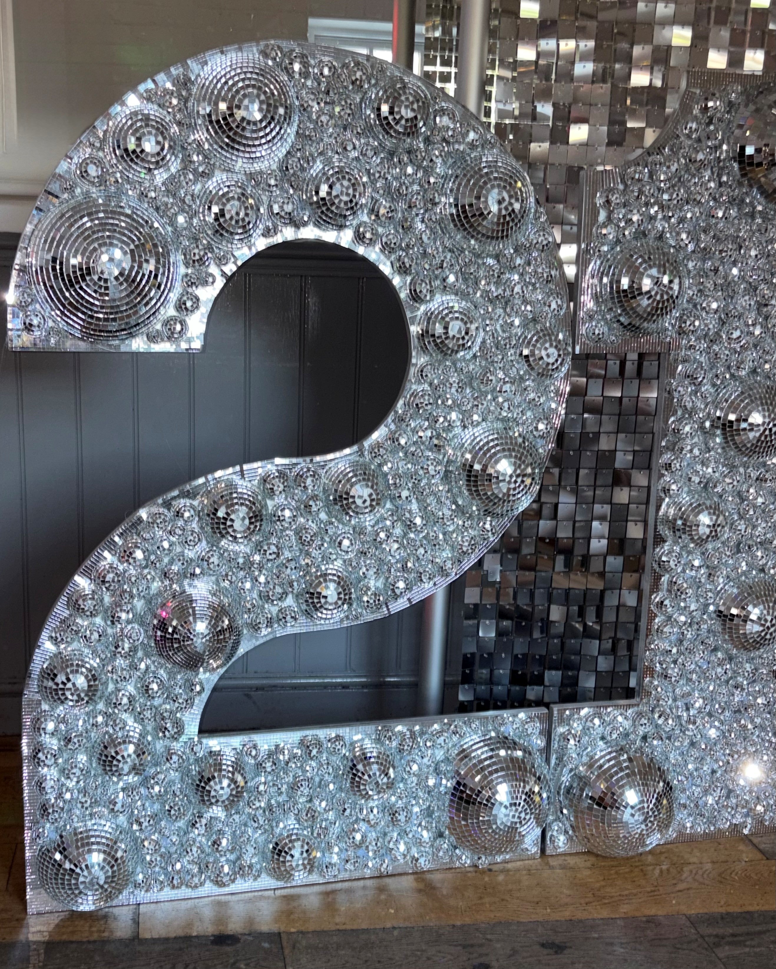 A large decorative number 2 sign covered in silver mirror tiles and disco balls